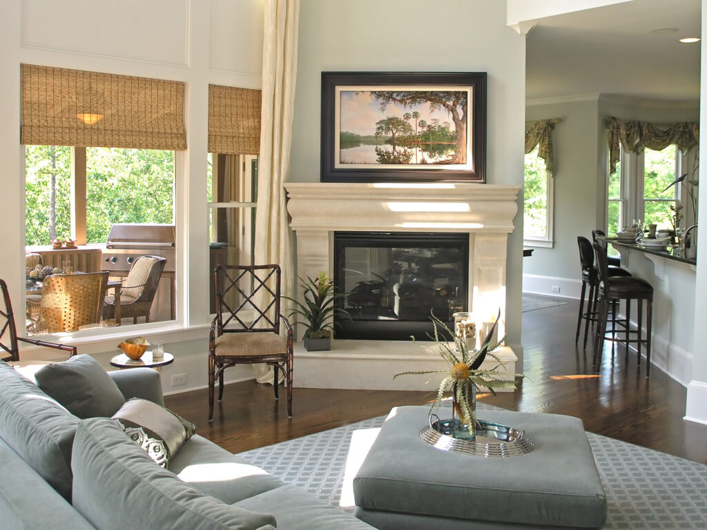 Living room with stone fireplace, gray sectional, and open kitchen view.